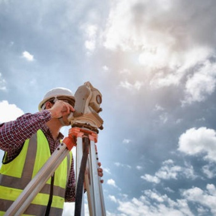 Surveyor Engineering. Surveyor using telescope at construction site, Surveying for making contour plans are a graphical representation of the lay of the land before startup construction work.